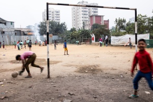 Dhaka - slum Sat Tola Bosti - Bambini dividono un campo di calcio pergiocare ai due sport preferiti, il calcio e il baseball